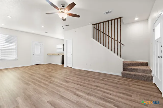 a view of empty room with wooden floor and fan