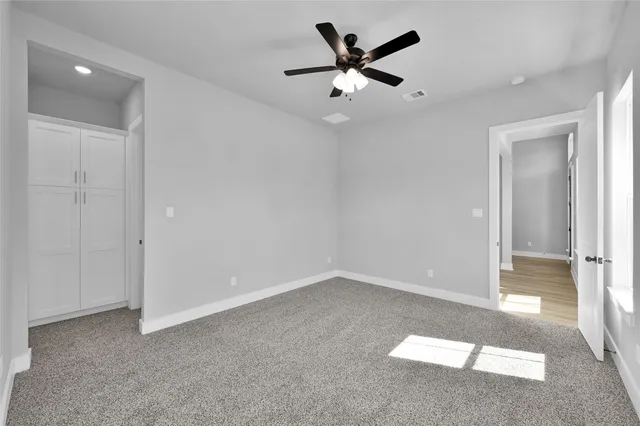 an empty room with closet and a ceiling fan