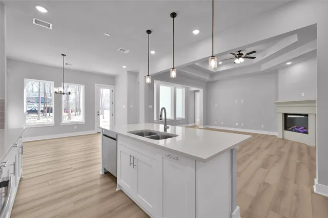 a large kitchen with kitchen island a stove a sink a center island and wooden floor