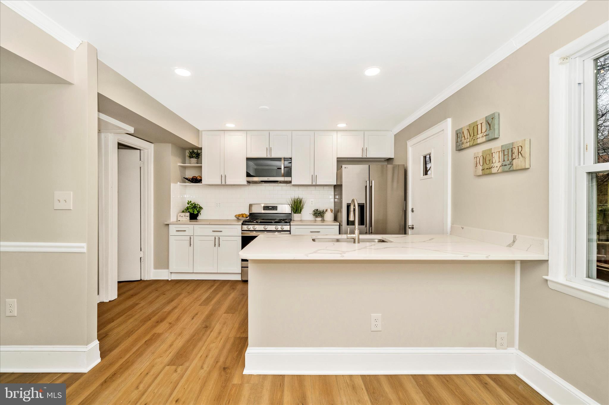 a kitchen with stainless steel appliances a sink a stove a refrigerator cabinets and a dining table