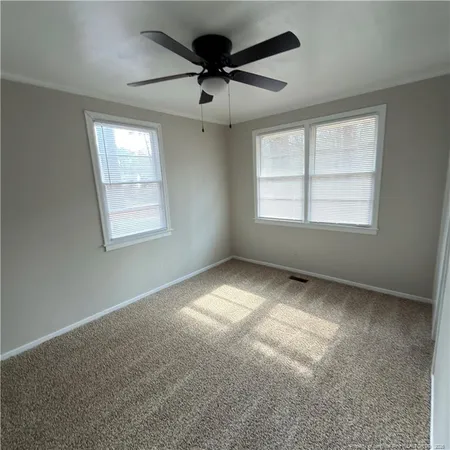 an empty room with windows and ceiling fan