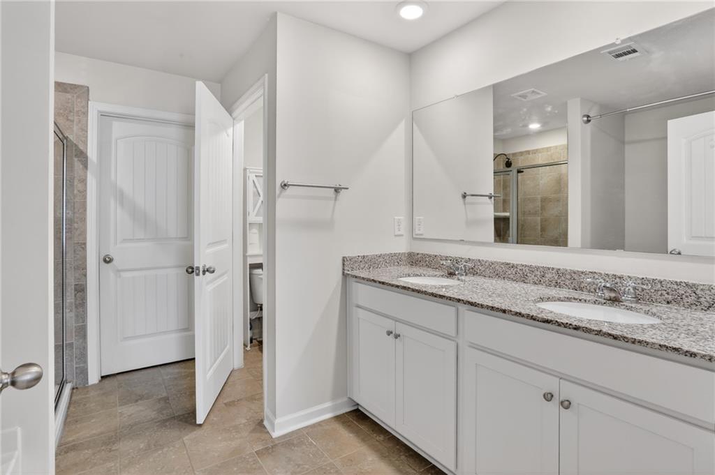 930 Sly Fox Run Fairburn, GA 30213 - Photo 17 of 28 a bathroom with a granite countertop sink two mirror and a shower