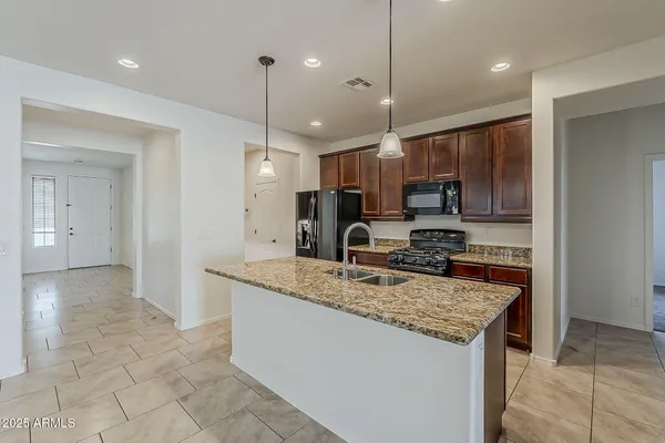 a kitchen with kitchen island granite countertop a sink a counter top space appliances and cabinets