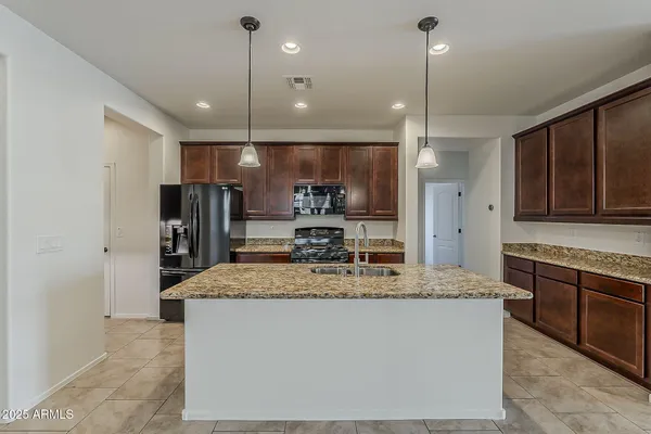 a kitchen with kitchen island granite countertop a sink a counter top space stainless steel appliances and cabinets
