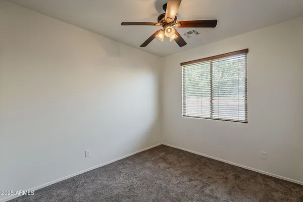 a view of an empty room and chandelier fan