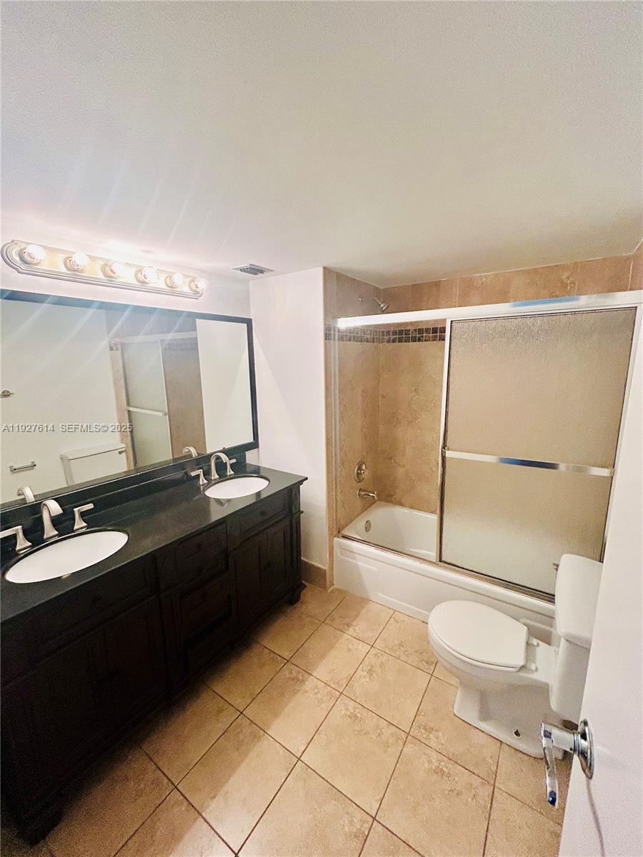 3100 West Rolling Hills Circle, Unit 310 Davie, FL 33328 - Photo 17 of 39 a bathroom with a double vanity sink toilet mirror and shower