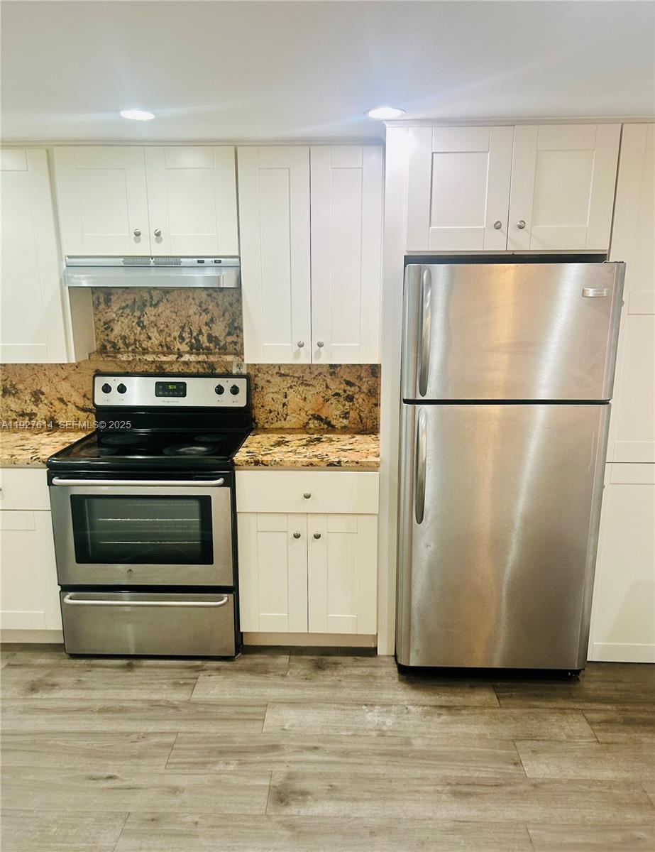 3100 West Rolling Hills Circle, Unit 310 Davie, FL 33328 - Photo 4 of 39 a white refrigerator freezer and a stove sitting inside of a kitchen with granite countertop stainless steel appliances