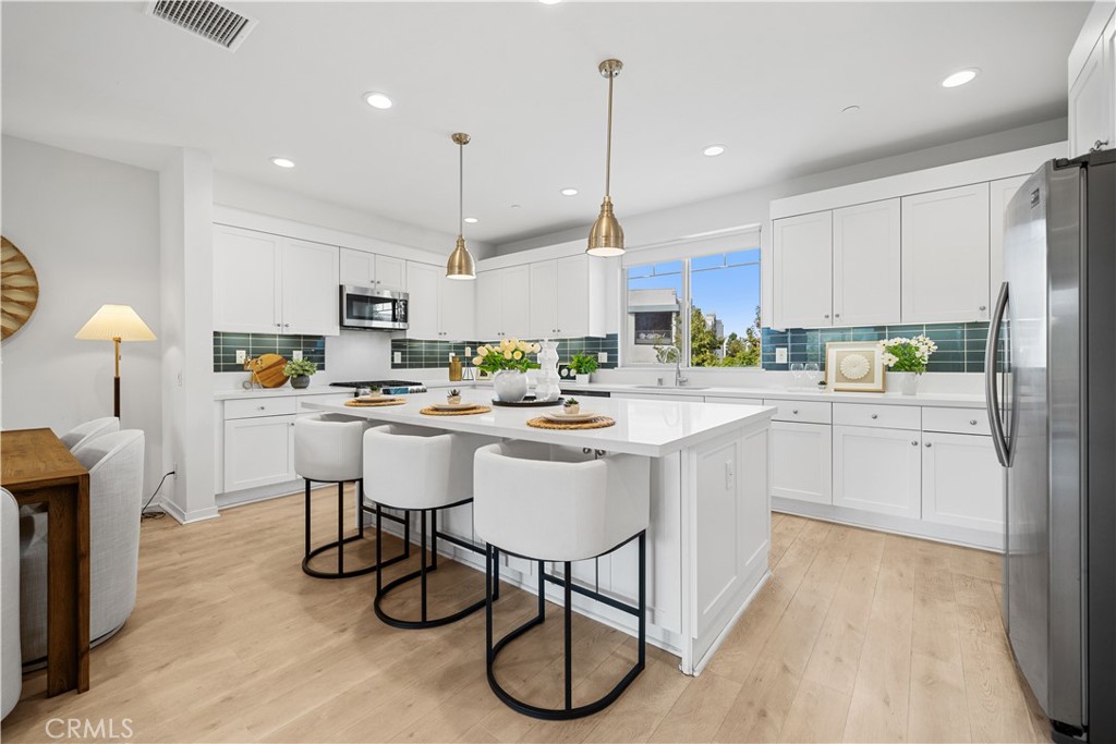 115 Episode Irvine, CA 92618 - Photo 14 of 43 a kitchen with stainless steel appliances kitchen island granite countertop a sink a stove a refrigerator and white cabinets with wooden floor