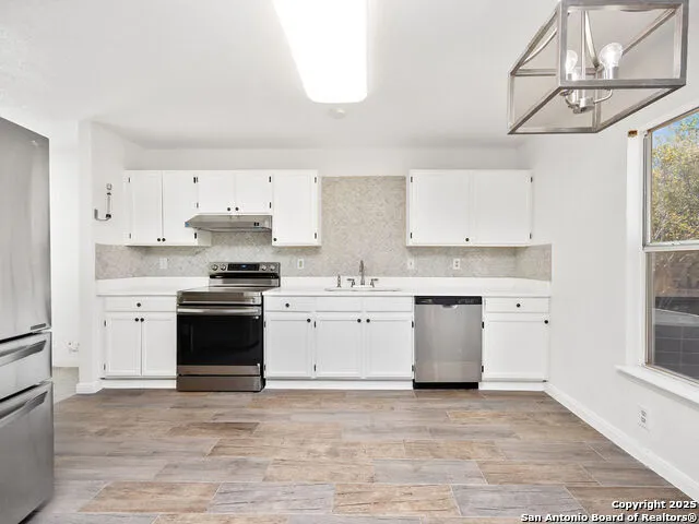 a kitchen with granite countertop a sink cabinets and stainless steel appliances