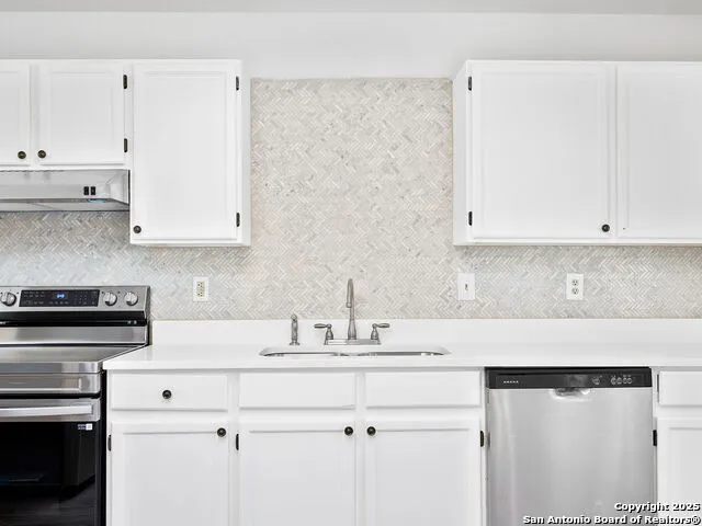 a kitchen with stainless steel appliances granite countertop white cabinets and a stove