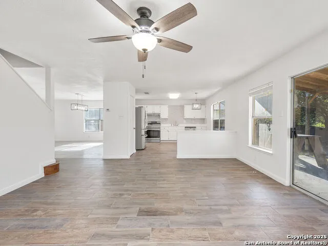 a view of an empty room with a window and kitchen view