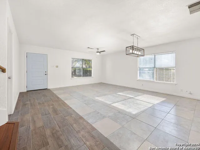 an empty room with windows and chandelier fan