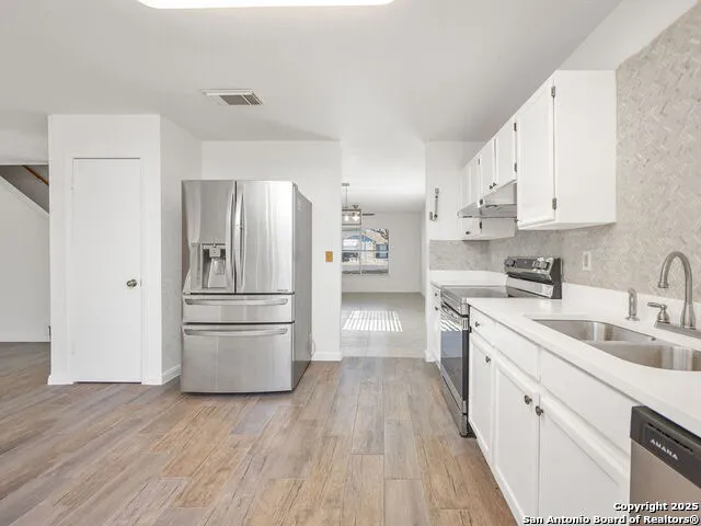 a kitchen with a refrigerator sink and cabinets