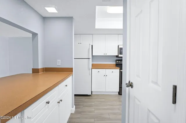 a kitchen with a refrigerator a stove and white cabinets