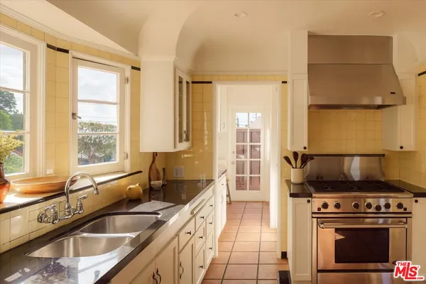 a kitchen with a stove a sink and a granite counter tops with wooden floors