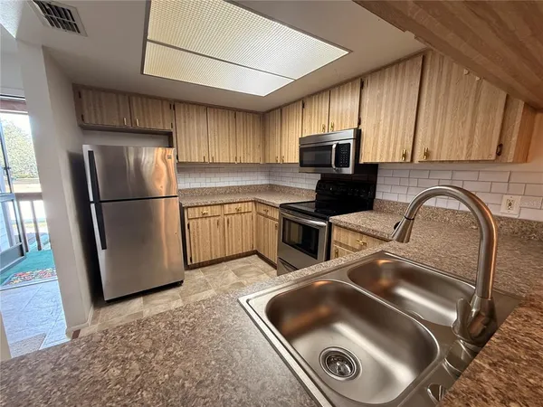 a kitchen with stainless steel appliances granite countertop a refrigerator a stove top oven a sink and dishwasher