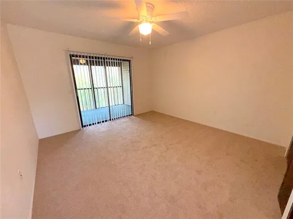 an empty room with windows and fan