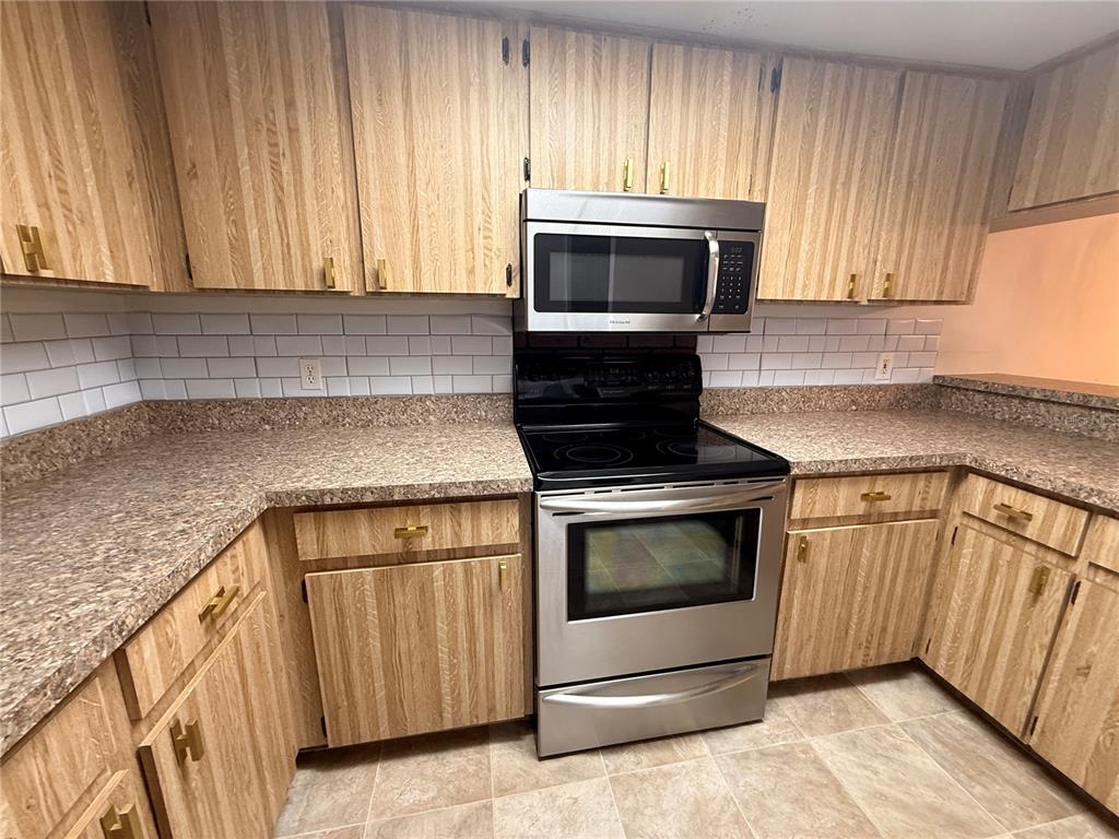 12155 Environmental Drive, Unit 6 New Port Richey, FL 34654 - Photo 9 of 42 a kitchen with granite countertop white cabinets and stainless steel appliances