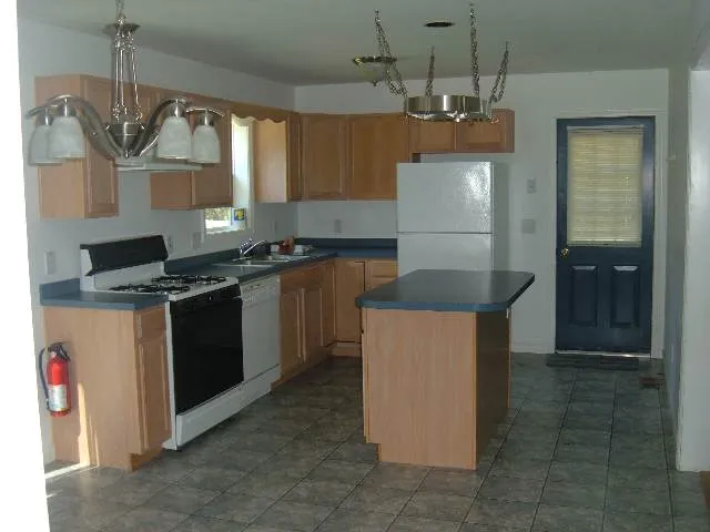 a kitchen with kitchen island granite countertop a sink a counter top space and cabinets