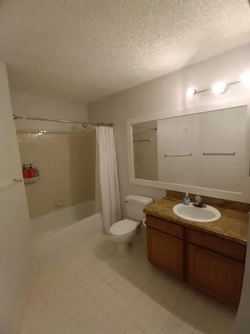 a bathroom with a granite countertop sink a toilet a mirror and shower