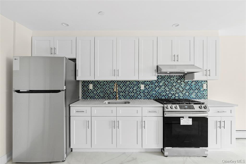 107-47 49th Avenue Queens, NY 11368 - Photo 6 of 41 a kitchen with white cabinets and stainless steel appliances