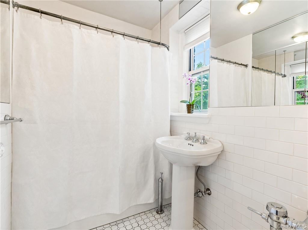 270 Bronxville Road, Unit B43 Bronxville, NY 10708 - Photo 22 of 36 a bathroom with a sink a mirror and a shower curtain