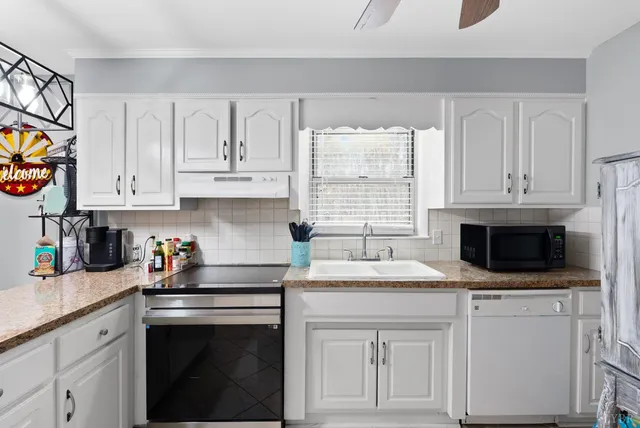 a kitchen with stainless steel appliances granite countertop a sink dishwasher a stove and a microwave oven with cabinets
