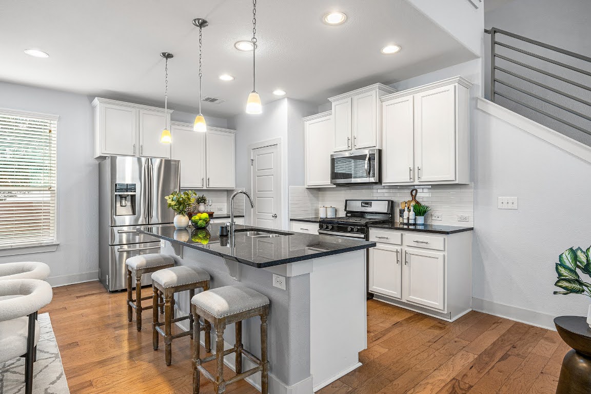 2315 Capulet Street Austin, TX 78741 - Photo 6 of 33 a kitchen with stainless steel appliances kitchen island granite countertop a stove a sink a refrigerator white cabinets and wooden floor