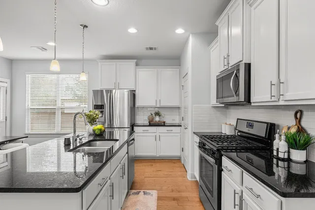 a kitchen with kitchen island granite countertop a sink a counter space appliances and cabinets