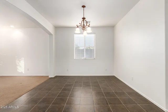 an empty room with chandelier fan and windows