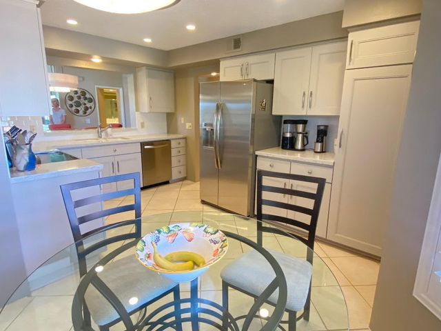 a kitchen with stainless steel appliances refrigerator dining table and chairs
