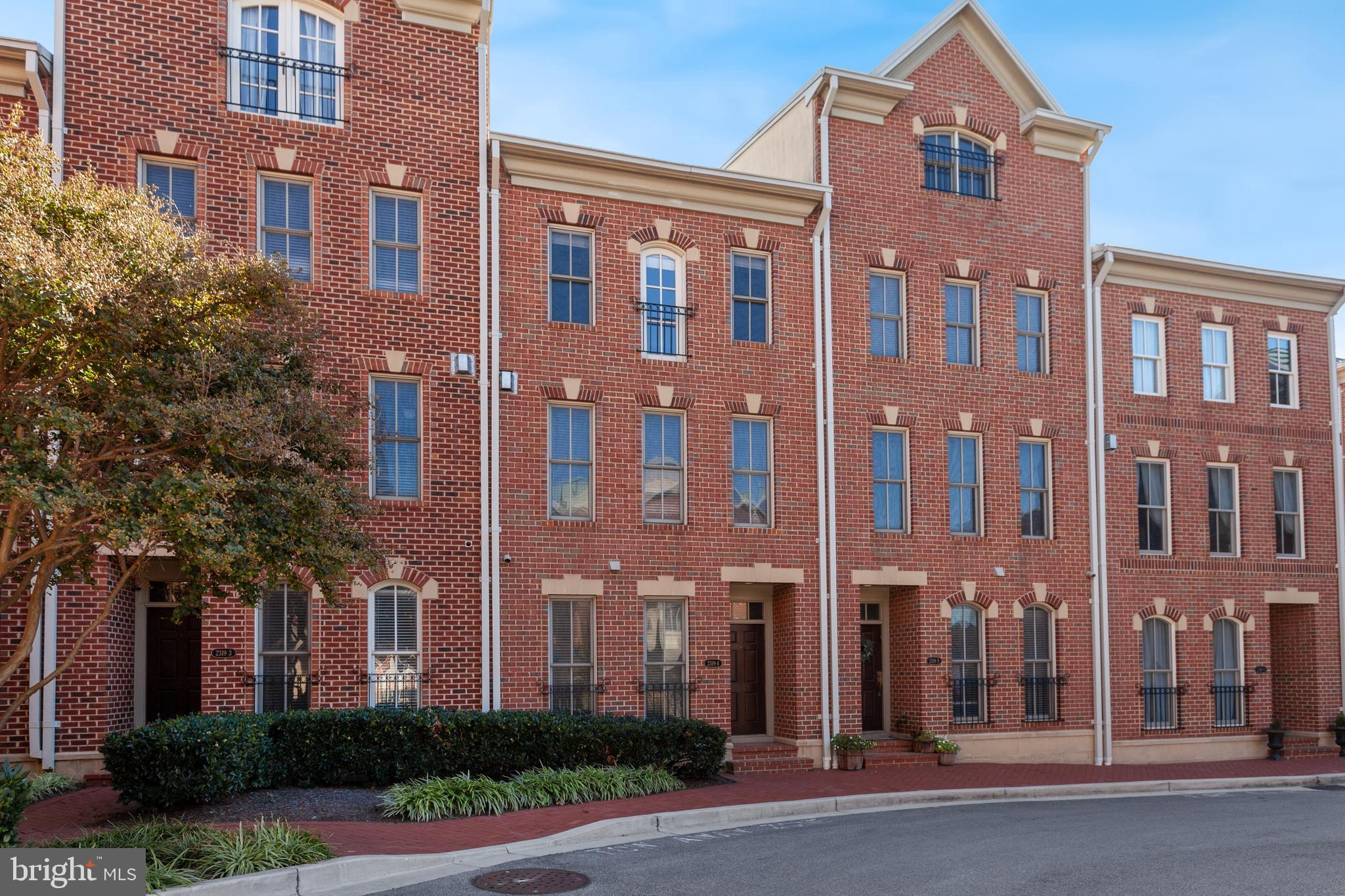 a front view of a multi story residential apartment building with a yard and plants