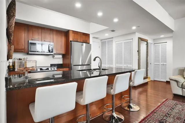 a kitchen with stainless steel appliances granite countertop a stove top oven a sink dishwasher a dining table and chairs with wooden floor