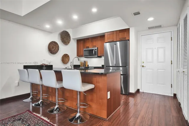 a kitchen with stainless steel appliances granite countertop a table chairs and a refrigerator
