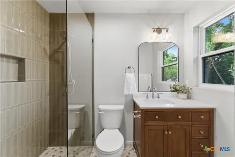 a bathroom with a toilet a sink a mirror a window and vanity