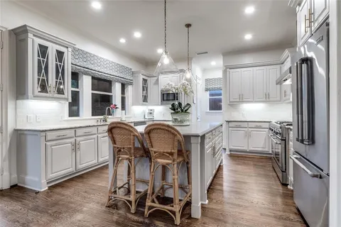 a kitchen with kitchen island granite countertop a sink a counter space stainless steel appliances and cabinets