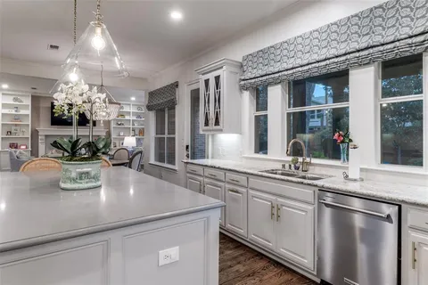 a large white kitchen with a sink and chandelier