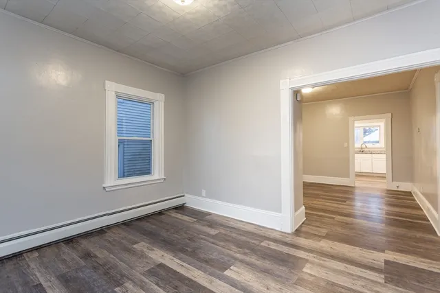 a view of an empty room with wooden floor and a window