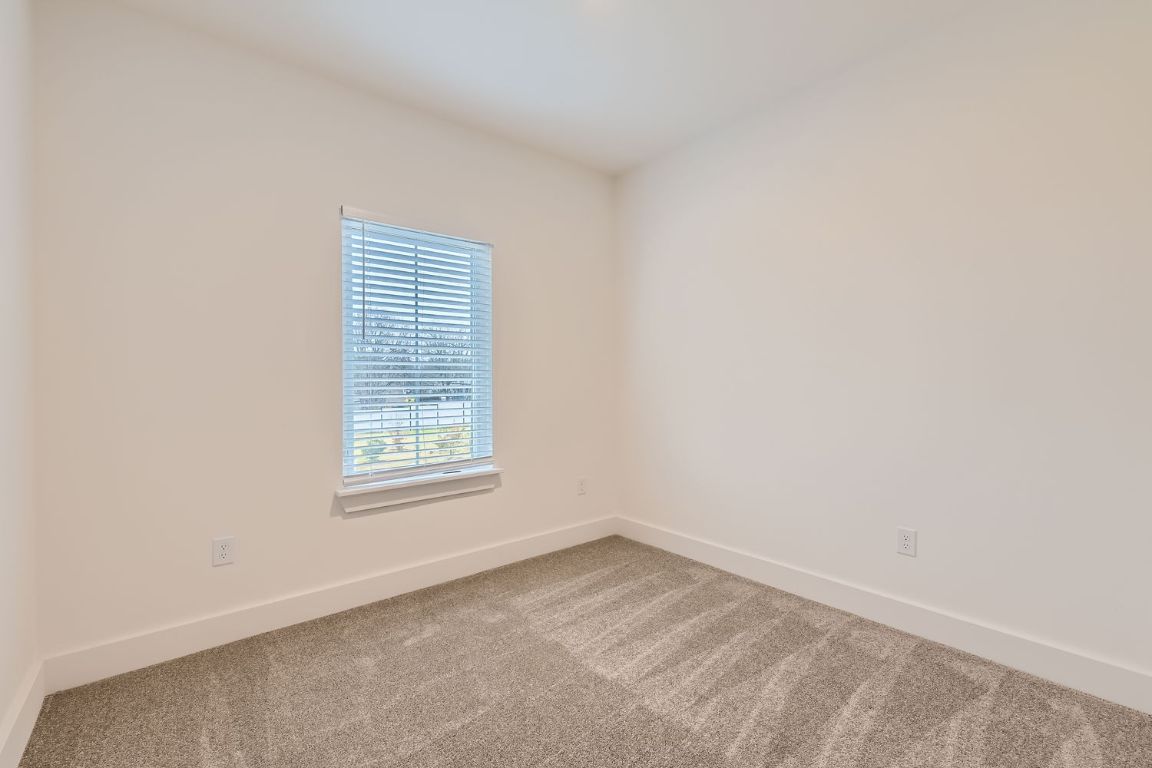 6820 Blue Dawn Trail, Unit 104 Austin, TX 78744 - Photo 7 of 9 Unfurnished room featuring baseboards and carpet floors