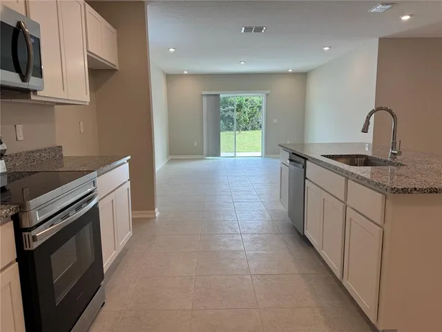 a kitchen with granite countertop a sink stove and cabinets