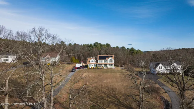 a view of a white house with a big yard and large trees