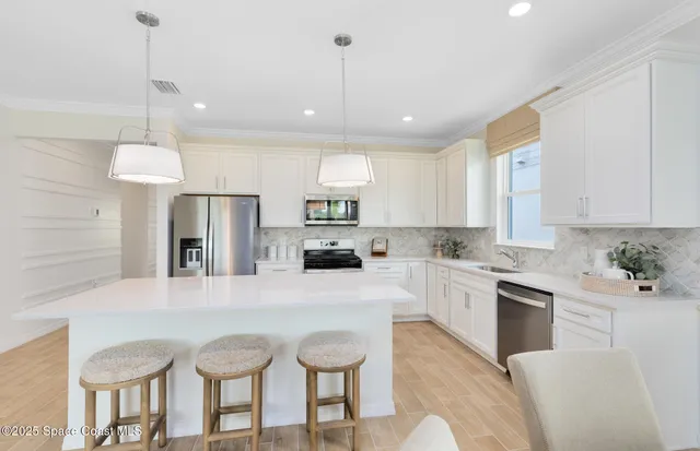 a kitchen with stainless steel appliances granite countertop a refrigerator a sink dishwasher a stove and white cabinets with wooden floor