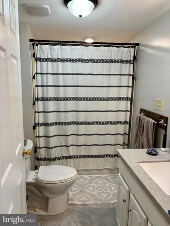 a bathroom with a granite countertop bathtub shower sink vanity and toilet