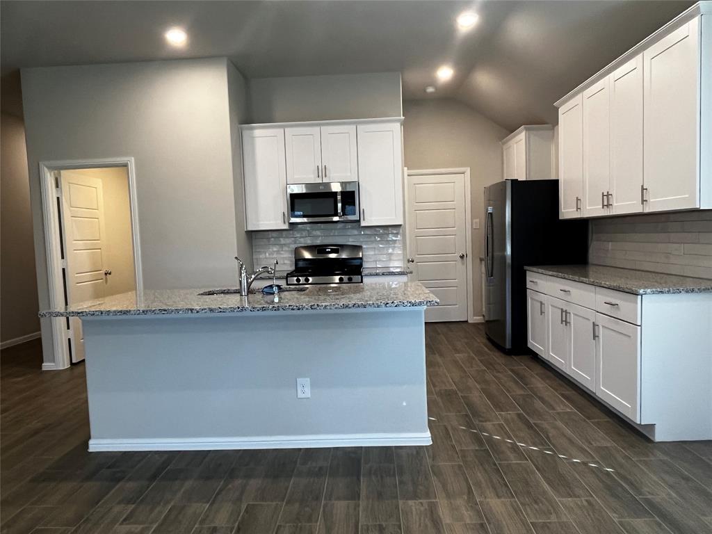 409 Wydown Drive Princeton, TX 75407 - Photo 11 of 29 a kitchen with stainless steel appliances a stove a sink a refrigerator and white cabinets