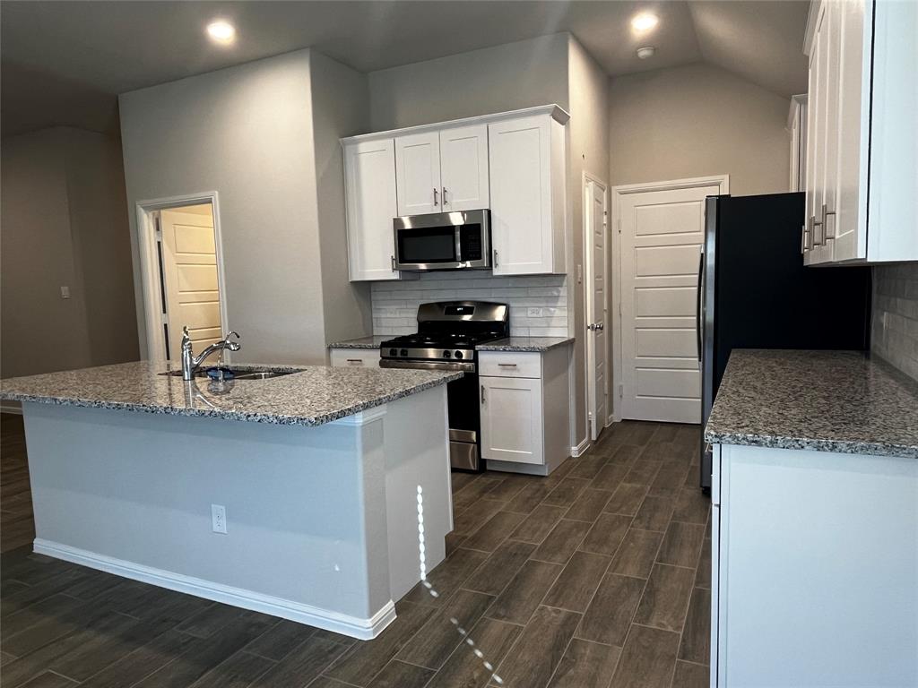 409 Wydown Drive Princeton, TX 75407 - Photo 12 of 29 a kitchen with kitchen island granite countertop a sink and steel appliances