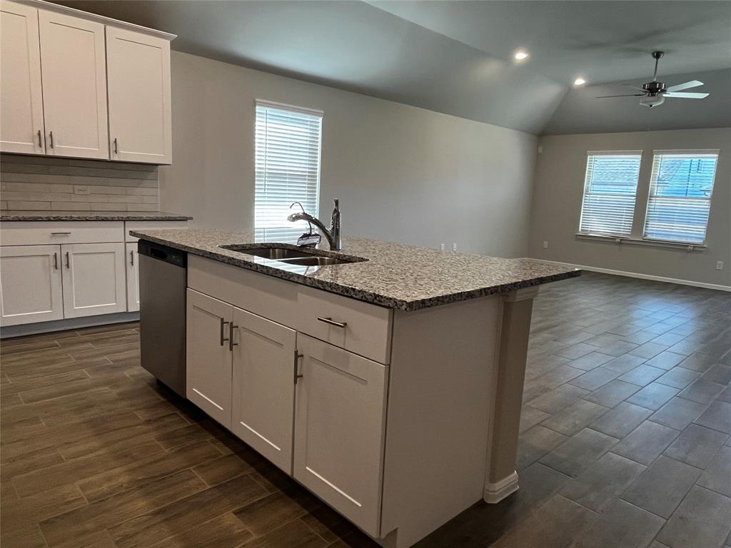 409 Wydown Drive Princeton, TX 75407 - Photo 20 of 29 a kitchen with stainless steel appliances granite countertop a sink a stove and white cabinets with wooden floor