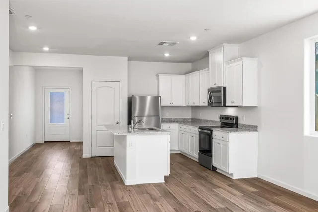 a kitchen with stainless steel appliances a microwave a stove a sink dishwasher and a refrigerator with wooden floor