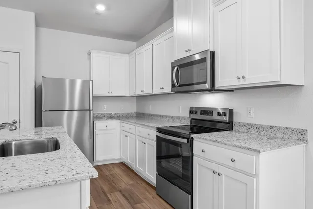 a kitchen with granite countertop a sink stove and refrigerator