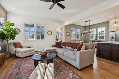 a living room with furniture kitchen view and a chandelier