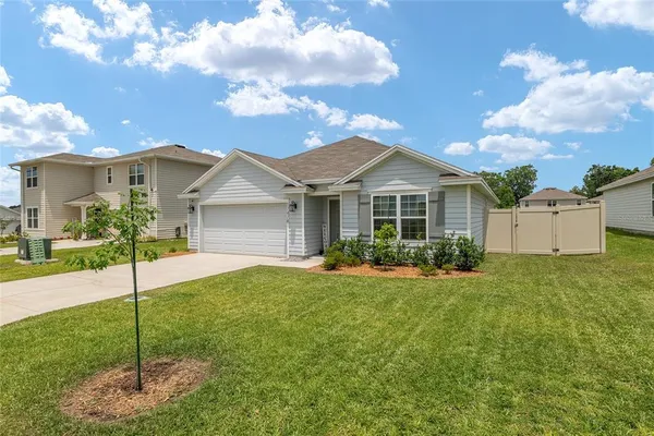 a view of a house with a big yard plants and large tree